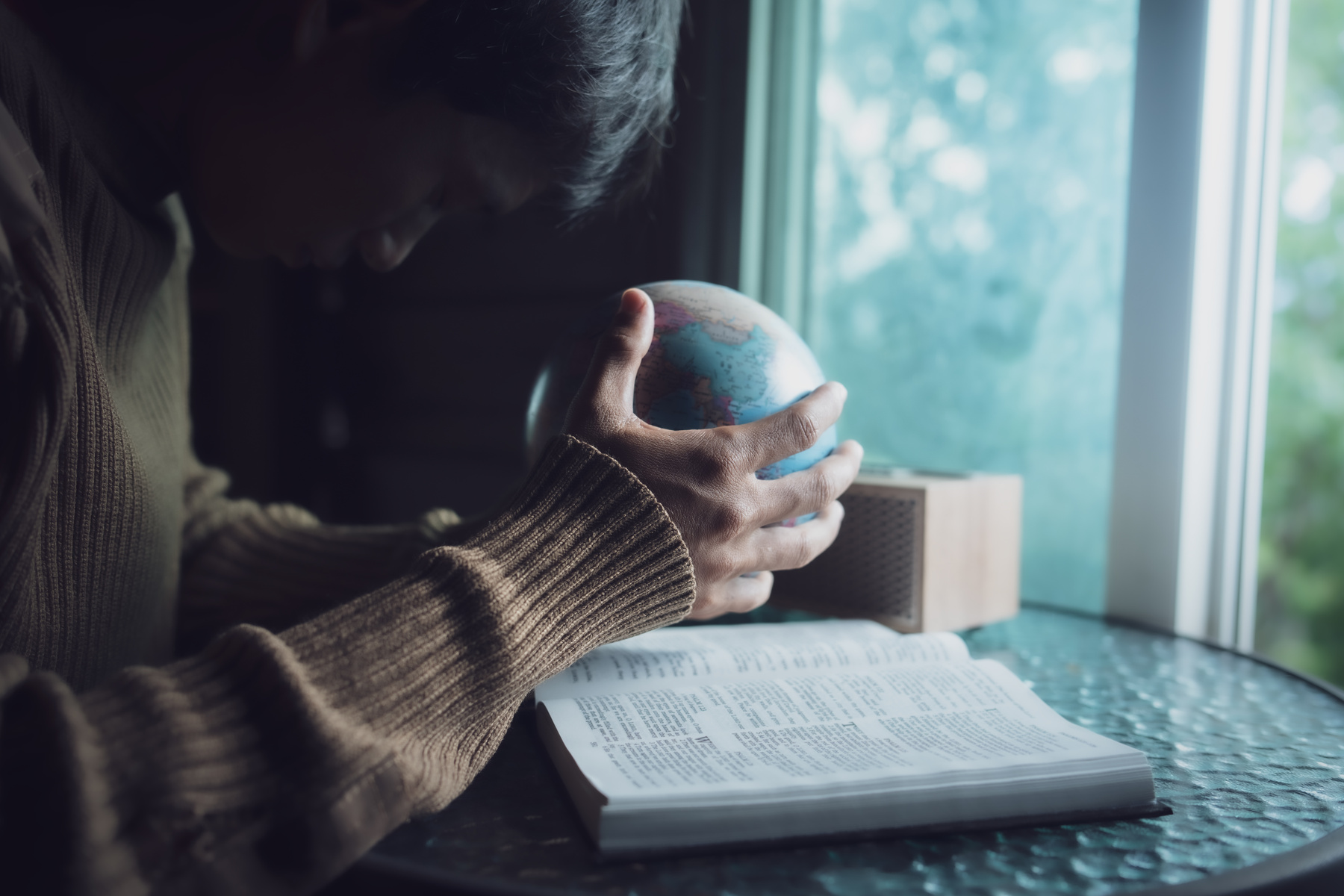 Man praying for globe and people around the world with bible in